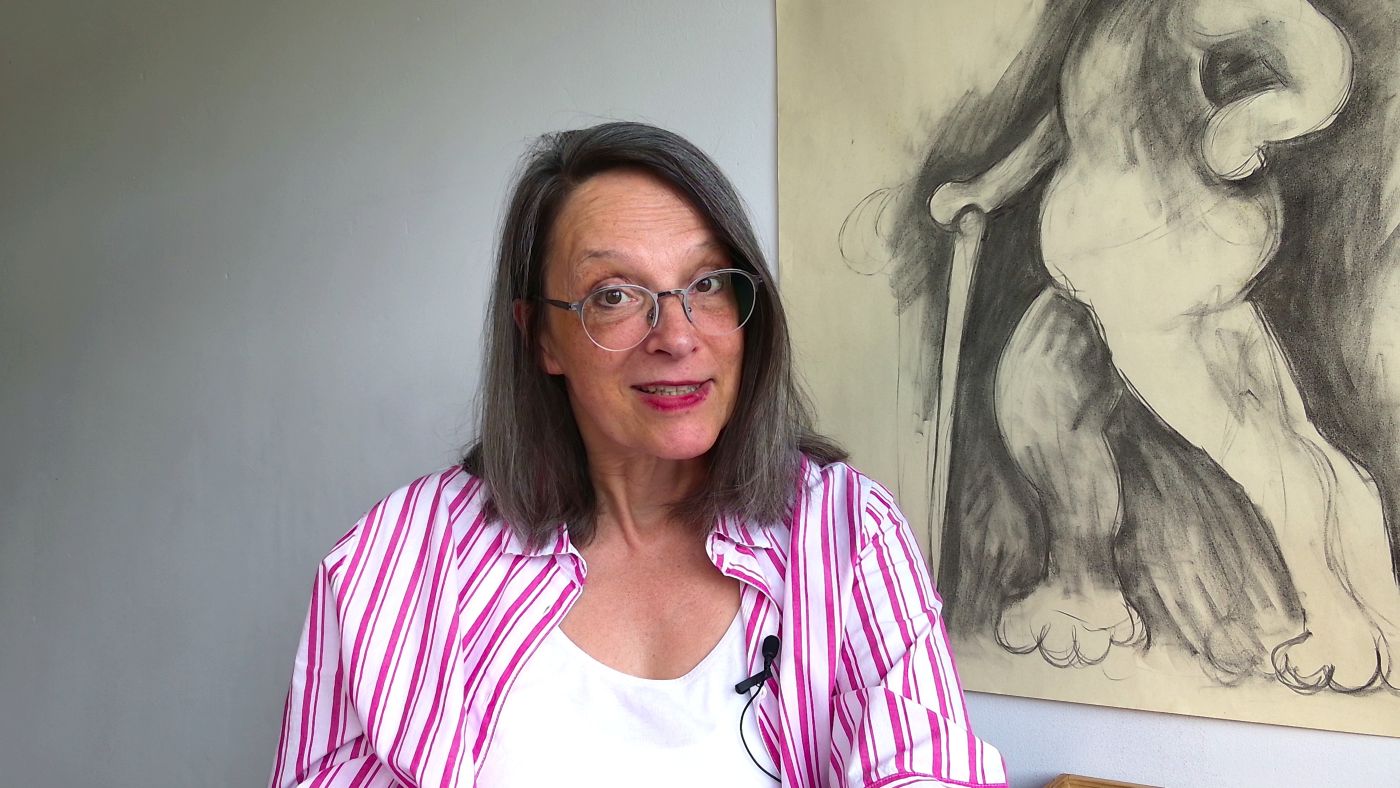 Maria best vor einer Kohlezeichnung im Atelier